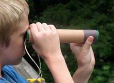 a young boy is looking through a telescope