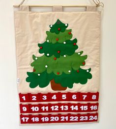 a wall hanging with a christmas tree on it's side and the numbers below