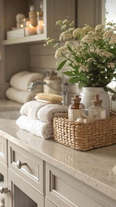 a bathroom counter with towels, soaps and flowers in a wicker basket on it