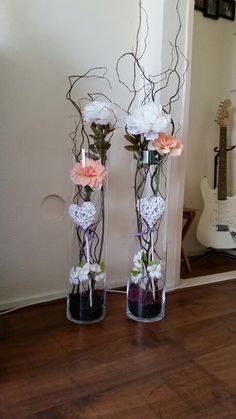 two vases filled with flowers on top of a wooden floor next to a mirror