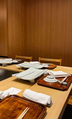 a wooden table topped with lots of plates and napkins next to a wall covered in wood paneling