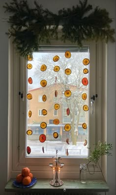 the window is decorated with oranges and pine cones