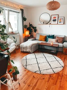 a living room filled with furniture and lots of plants on top of a hard wood floor