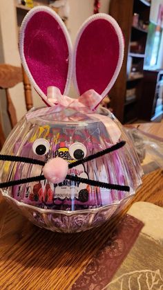 a plastic easter egg decorated like a bunny with ears and eyes on it's head