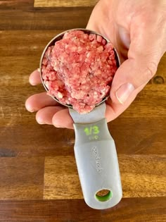 a person holding a measuring scale with meat in it