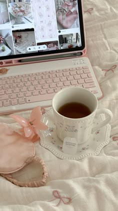 a laptop computer sitting on top of a bed next to a cup of coffee