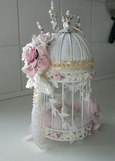 a white birdcage with pink flowers and pearls