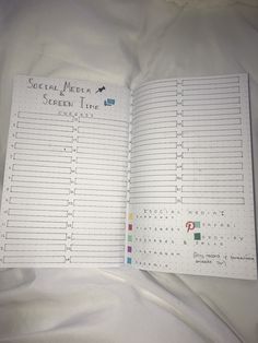 an open planner book sitting on top of a white sheet with writing in the pages