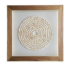 a white and brown beaded artwork in a wooden frame