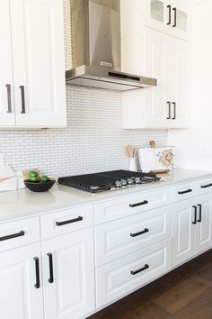 a kitchen with white cabinets and black handles on the stove top is seen in this image