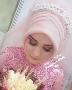 a woman wearing a pink hijab holding a bouquet of flowers