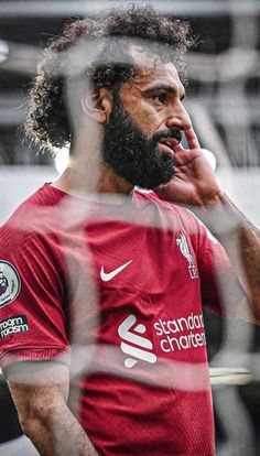 a man with a beard is talking on the phone while holding a soccer ball in his hand