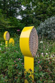 yellow mailboxes are lined up in the grass near flowers and trees, along with wildflowers