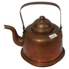 an old tea kettle with a price tag on the top and bottom, sitting on a white background