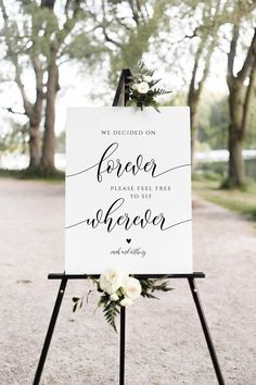 a welcome sign for an outdoor wedding with white flowers and greenery on the top