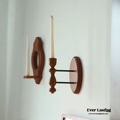 two candles are lit on the wall next to a candle holder that is shaped like an oval