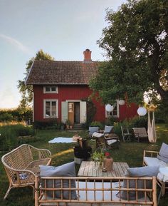 a red house sitting on top of a lush green field next to a wooden table