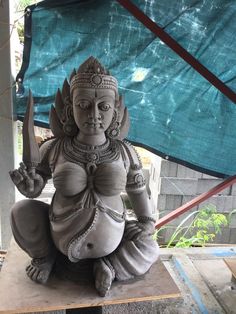 a statue sitting on top of a wooden table next to a blue tarp covered wall