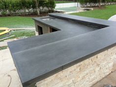 an outdoor kitchen with black counter tops and green grass in the backgroung