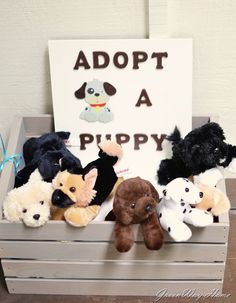 a crate filled with stuffed animals sitting next to a sign that says adopt a puppy