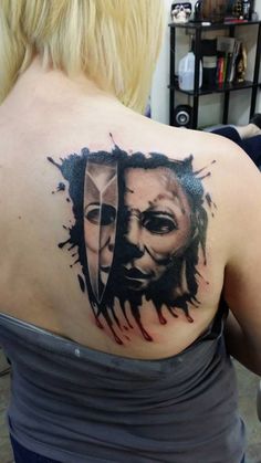 a woman with a tattoo on her back shoulder and the image of two faces painted on it