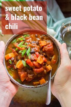 two hands holding a bowl of soup with beans, carrots and celery