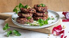 some meat patties on a plate with parsley and red onion garnish