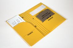 an open yellow folder with some paper attached to the front and back cover, sitting on a white surface