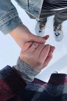 two people holding hands in the snow with their feet on each other's hand