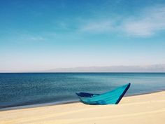 a blue boat sitting on top of a sandy beach