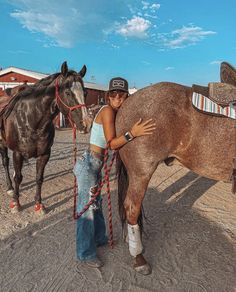 a woman is standing next to a horse and holding the reins with her hand on it