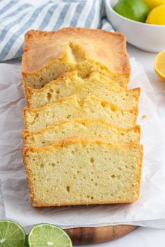 slices of lemon pound cake sitting on top of a cutting board next to sliced limes