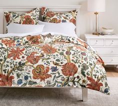 a bed with an orange and white floral comforter