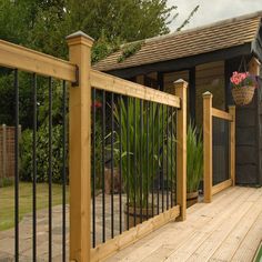 a wooden deck with wrought iron railings and potted plants on the other side