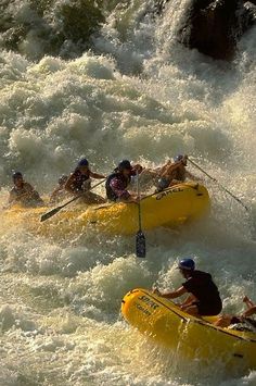 three people in yellow rafts paddling through rapids