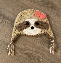 a crocheted hat with a slotty on it's face and a bow