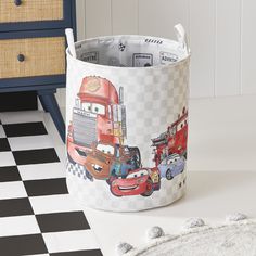 a toy basket with cars on it sitting next to a black and white checkered floor