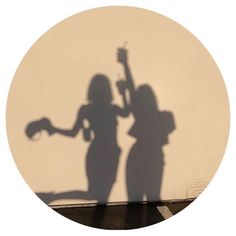 two people standing next to each other with their shadows on the wall and one person holding a cell phone