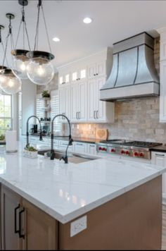 a large kitchen with white cabinets and marble counter tops