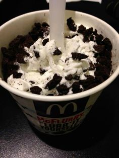 an ice cream sundae with oreo cookies and whipped cream in a paper cup