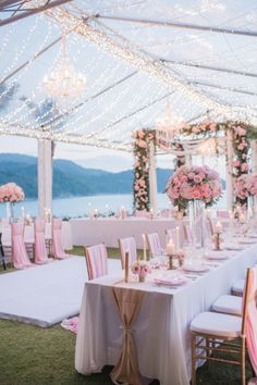 an outdoor wedding set up with white and pink flowers on the aisle, overlooking the ocean