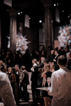 a group of people standing around each other in a room filled with tables and chairs