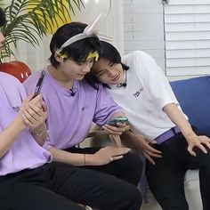 three people sitting on a couch looking at their cell phones