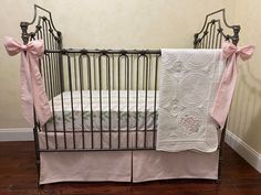 a baby crib with pink and white bedding on it's side, next to a wooden floor