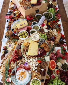 an assortment of food is laid out on a long table with cheeses, crackers and nuts