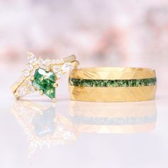 two gold rings with green and white stones on them, one is shaped like an arrow