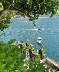 boats are in the water near some trees and bushes with people standing on top of them