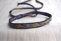 two blue and yellow bracelets sitting on top of a white cloth covered tablecloth