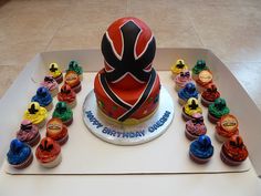 a birthday cake surrounded by cupcakes on a table