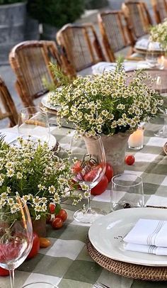 the table is set with plates, glasses and vases filled with flowers on it